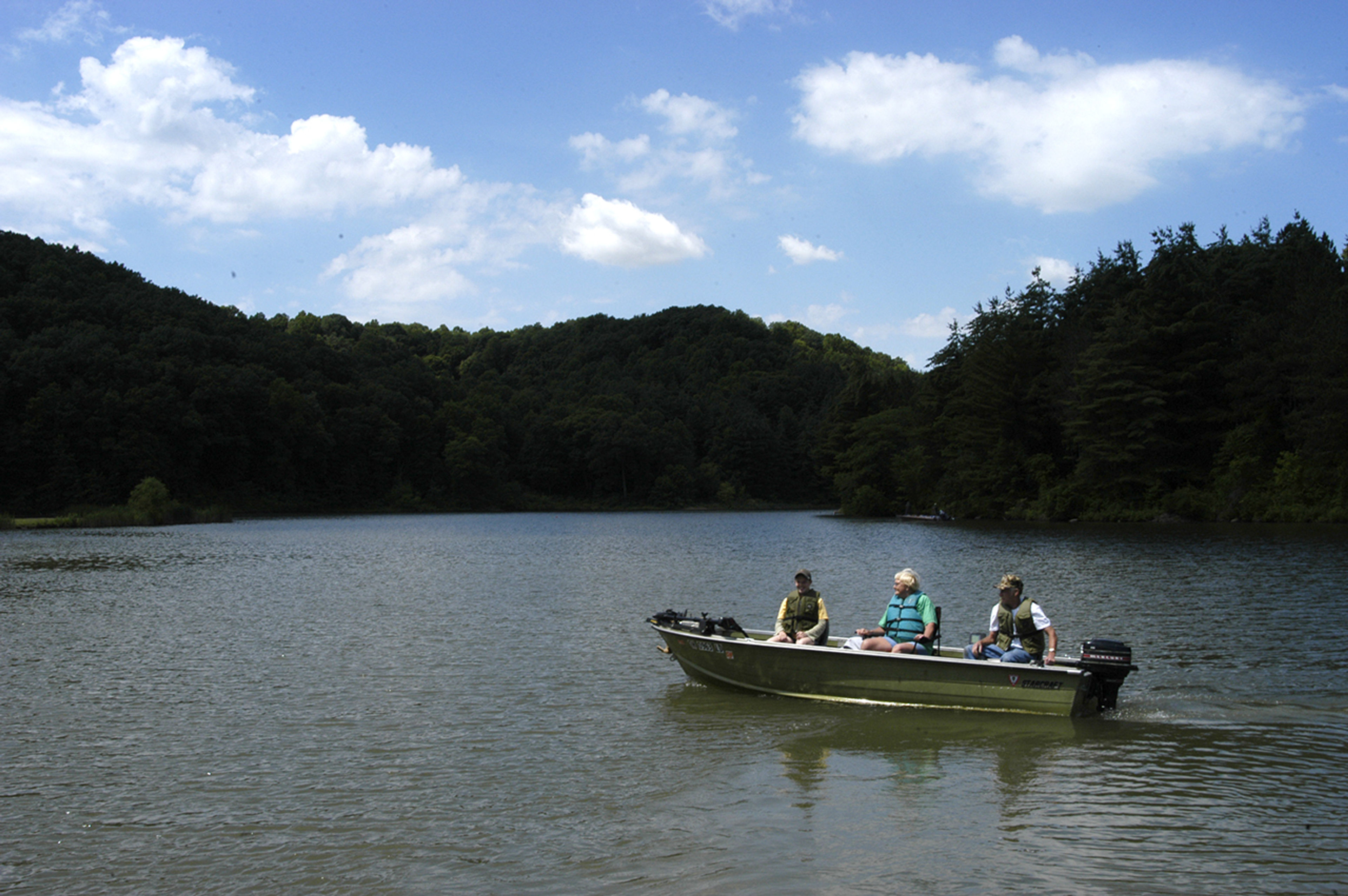 A group of people in a boat on a lake at Strouds Run State Park