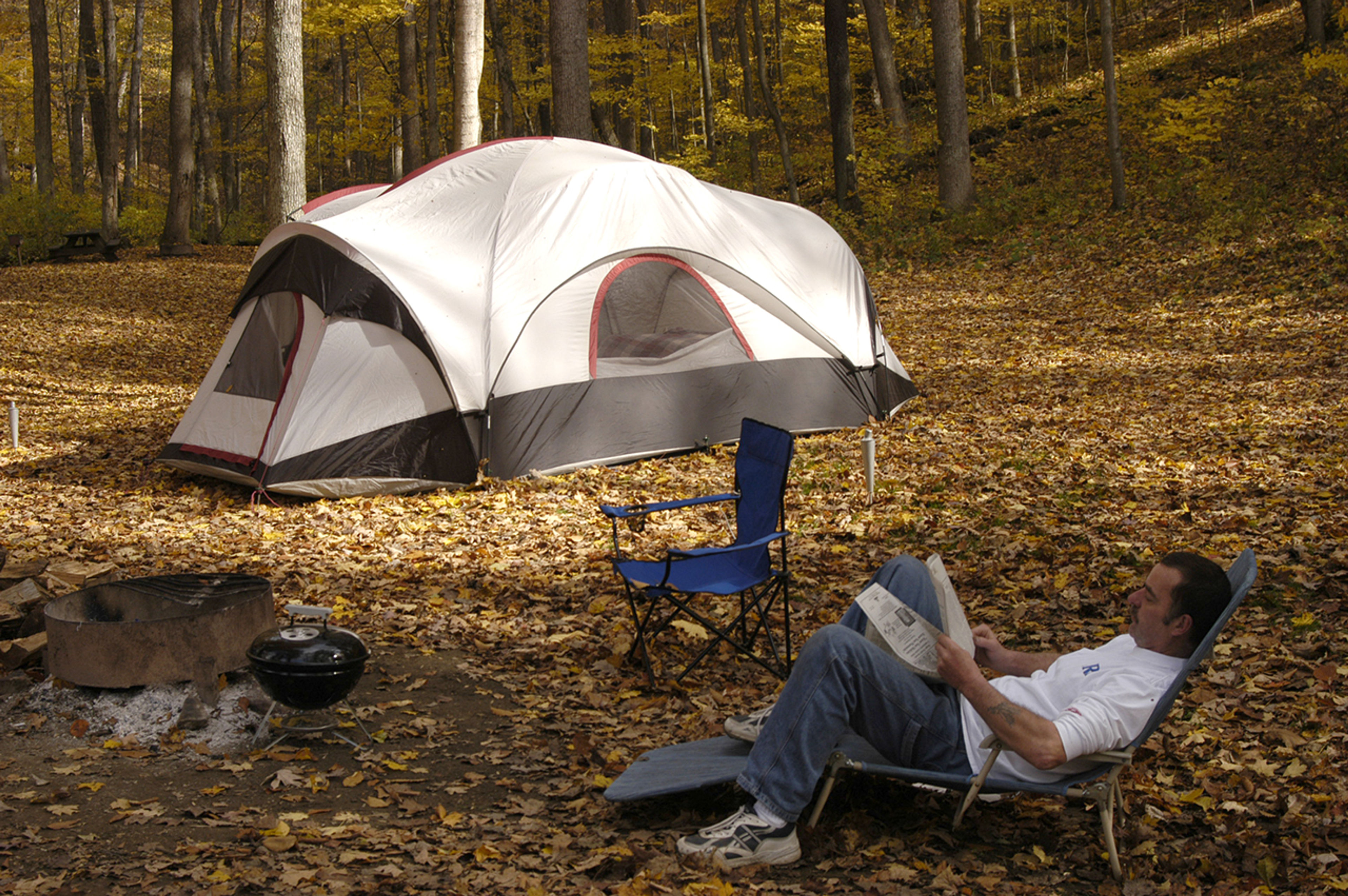 A person sitting in a chair next to a tent at Tar Hollow State Park