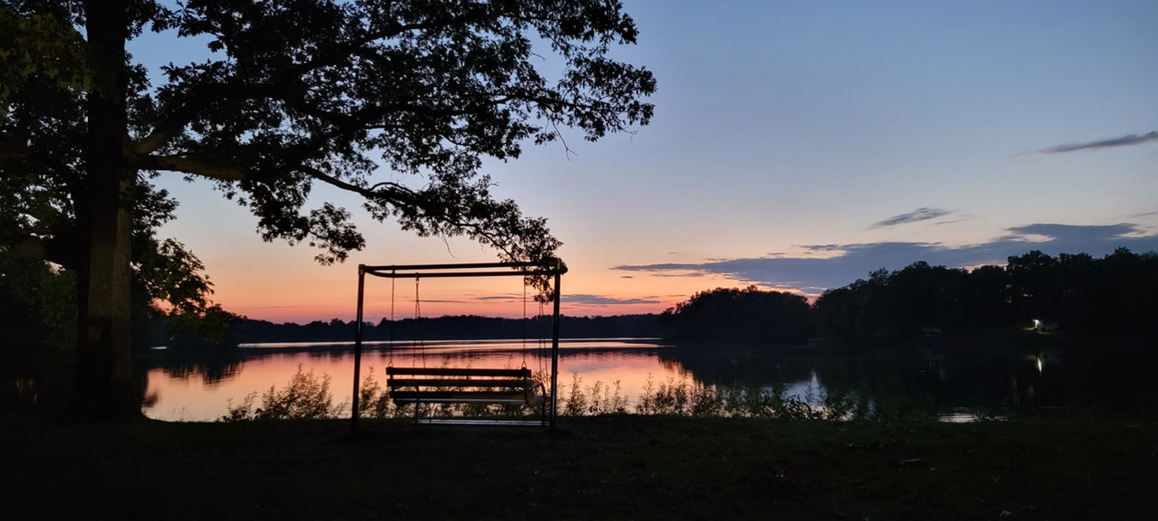 Porch swing by a tree in front of a lake at Wingfoot Lake State Park