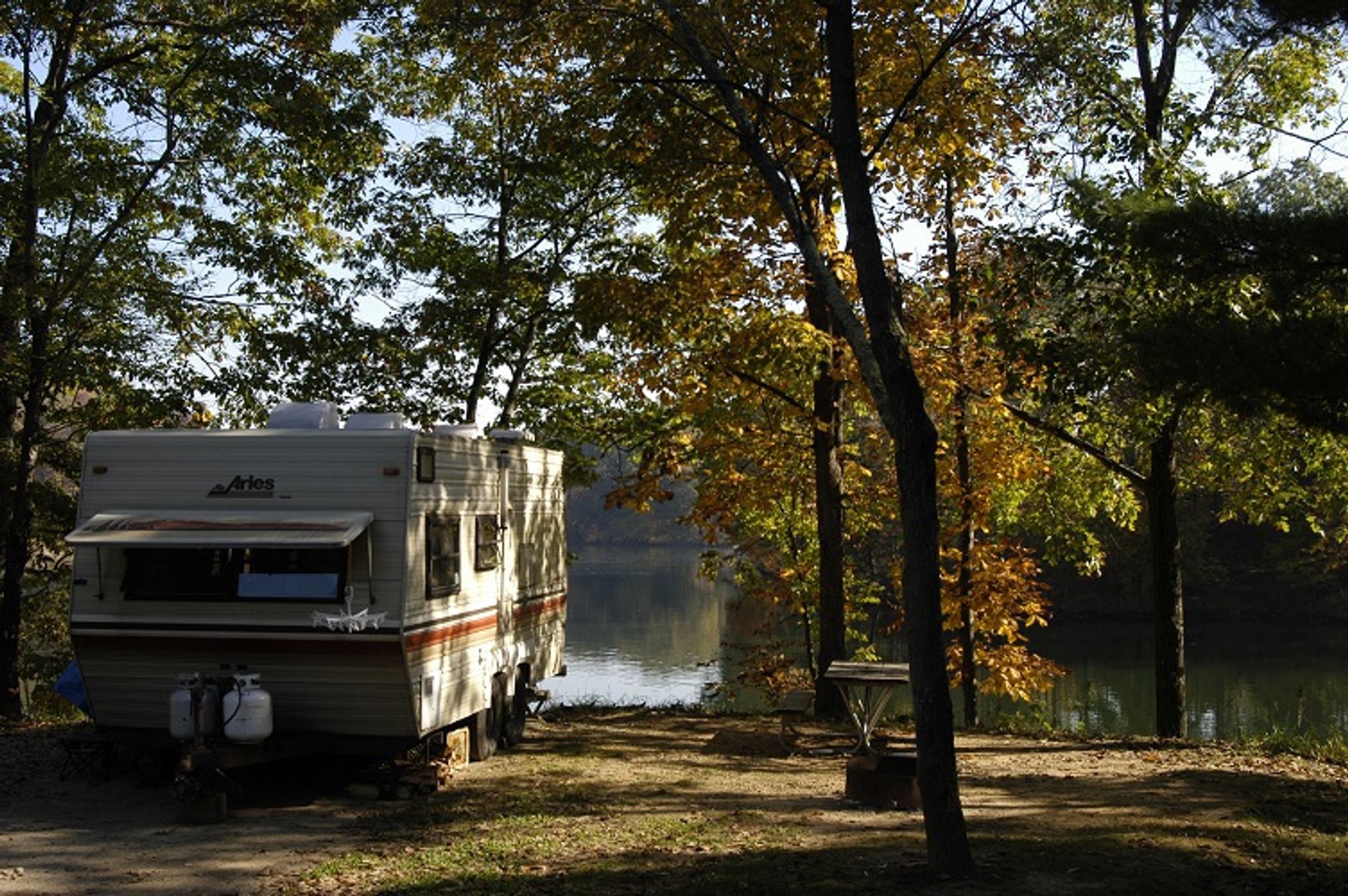 RV parked near a body of water surrounded by trees at Wolf Run State Park