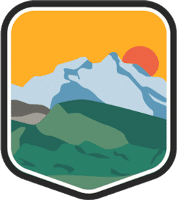 An illustrated badge for the Alaska community featuring a vast mountain range with snow-capped peaks with the sun setting behind the range.