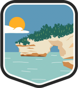 An illustrated badge for the Michigan community showing a lakeside rock formation with scrub on top and a clear blue sky.