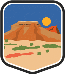 An illustrated badge for the Oklahoma community featuring a flat desert prairie landscape with a butte and a setting sun in the background.