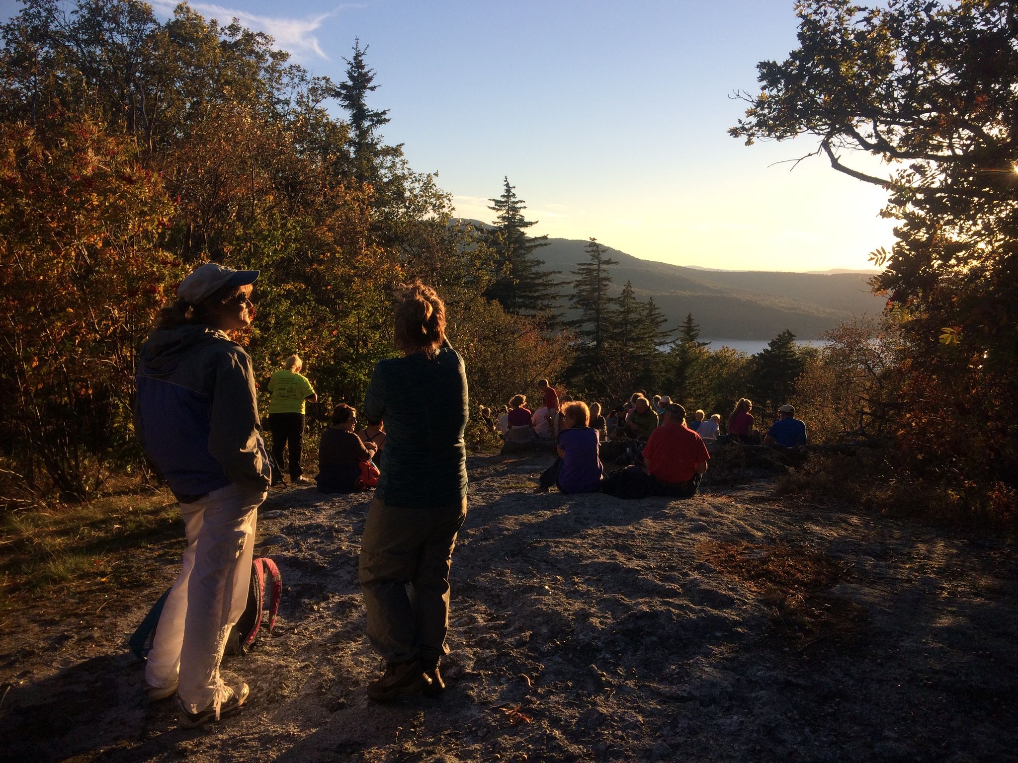 A group gathers at sunset on Sunset Hill overlooking the lake.