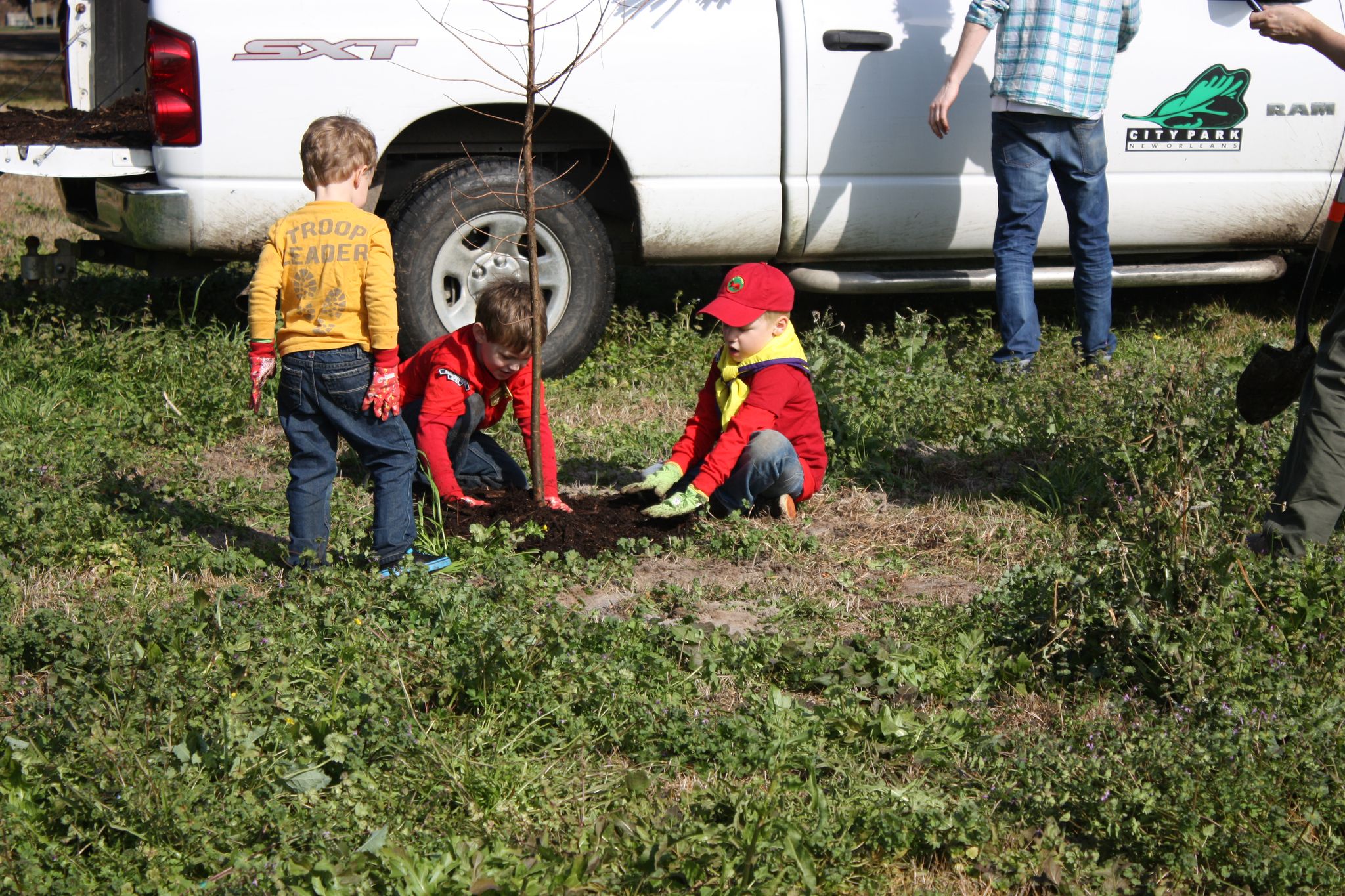 Children planting a tree with the Volunteer Coordinator