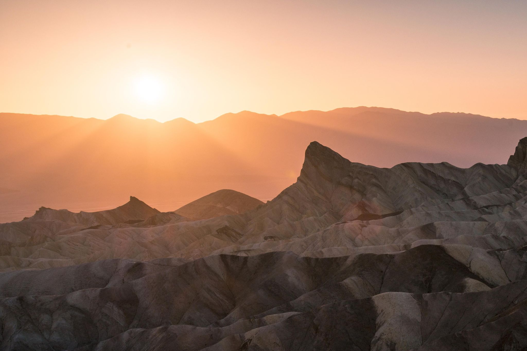 The warm light of sunset covers the badlands at Zabriskie Point.