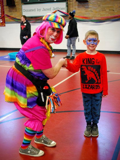Photo of colorful Clown shaking hands with a small child.