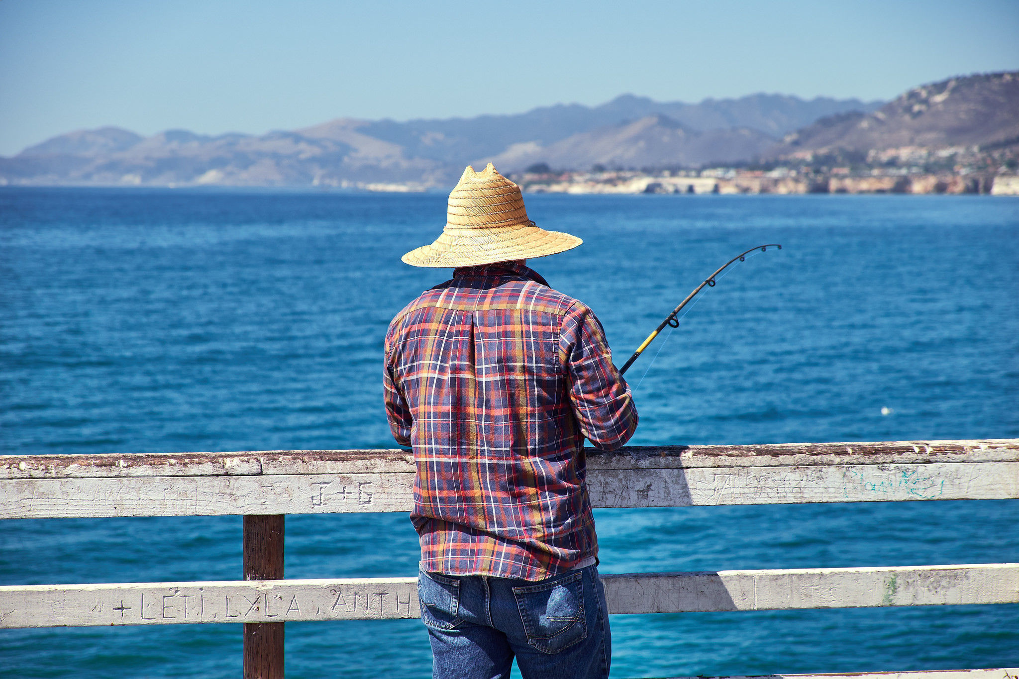 Photo of a man fishing off of the pier at Pismo State Beach.