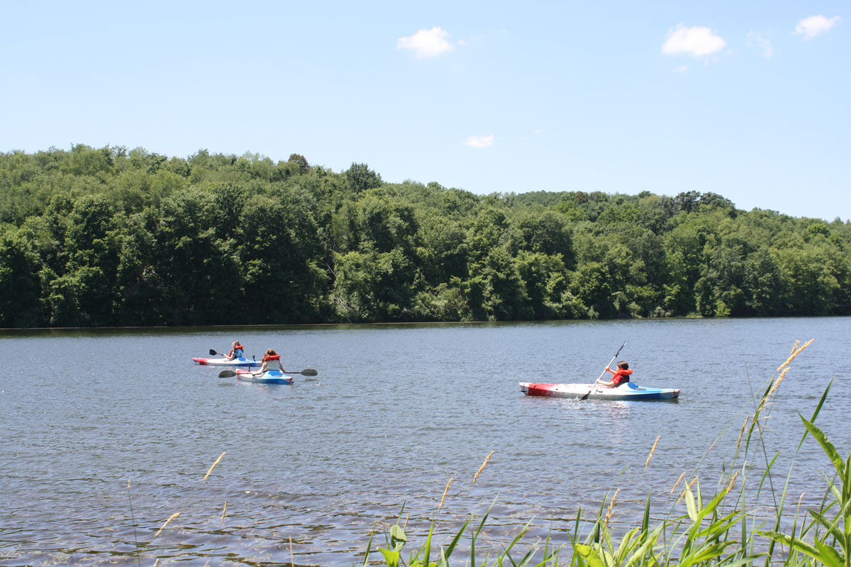 summer day with 3 people kayaking on Barkcamp Lake