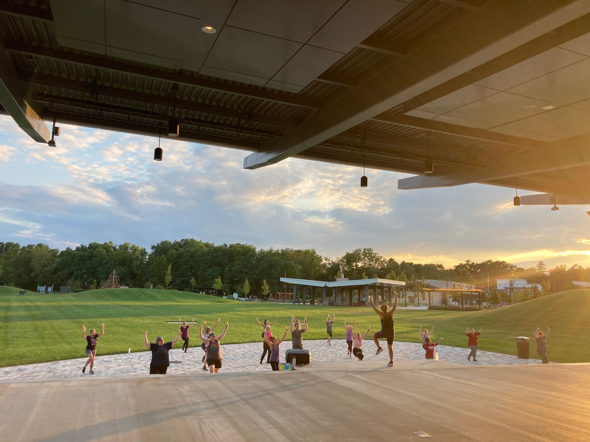 Overlooking group of adults engaging in dancing on performance stage at Switchyard Park at sunset