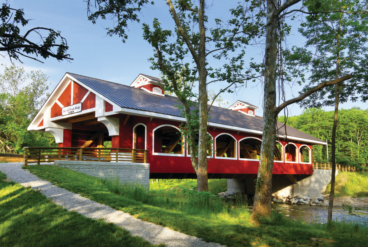 A red covered bridge over a body of water at Hueston Woods State Park