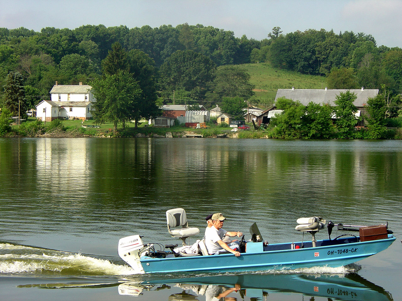 Two older men in a speed boat on a body of water at Lake Logan State Park