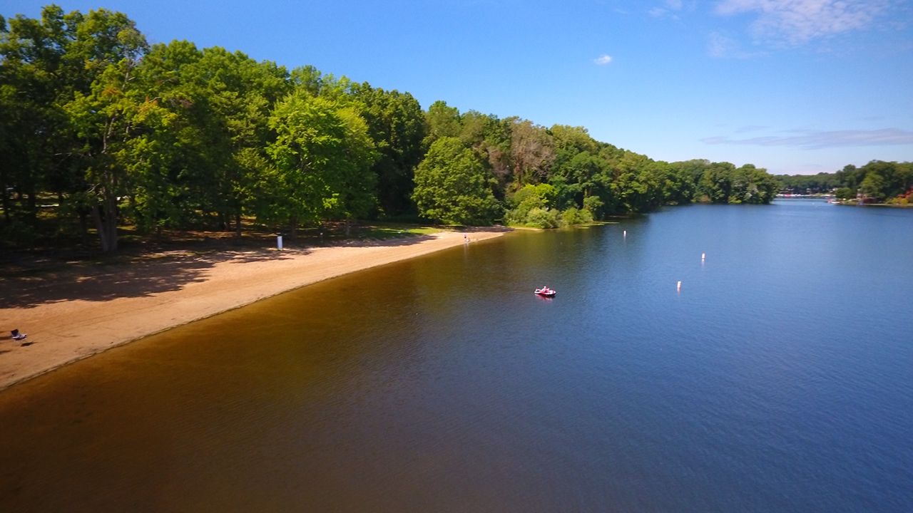 A body of water with trees and a boat on it at Portage Lakes State Park