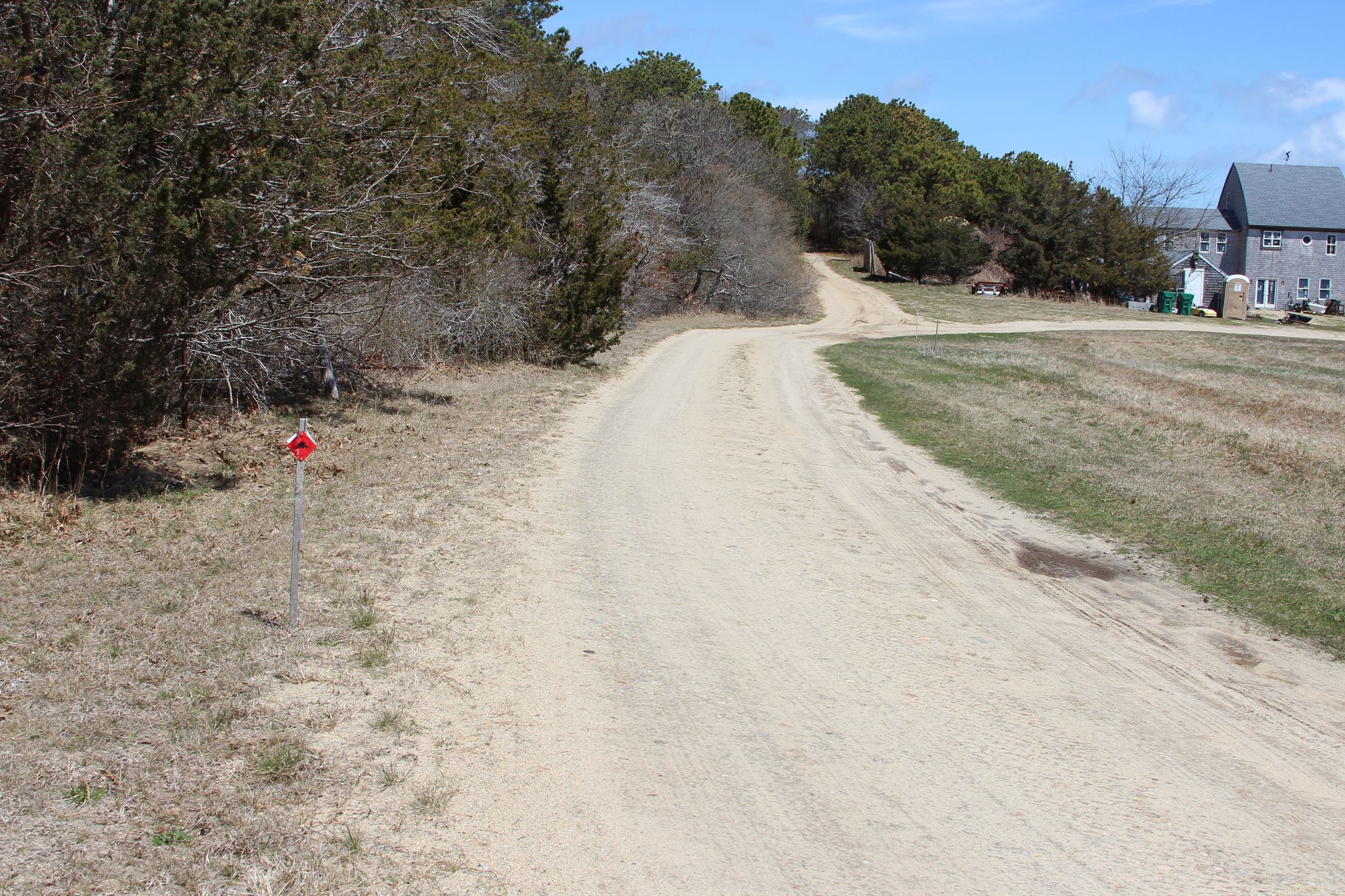 dirt road path running to the left of a house